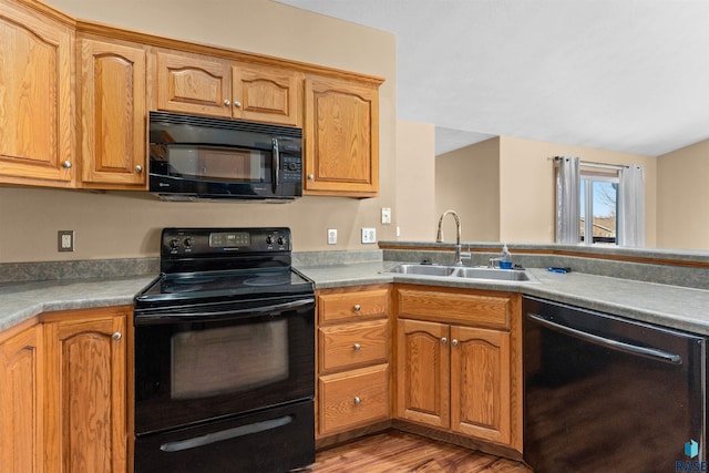 kitchen with black appliances, light hardwood / wood-style floors, and sink