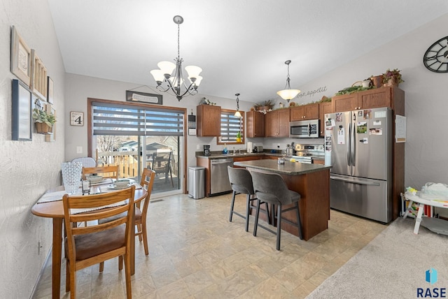 kitchen with a chandelier, a breakfast bar area, appliances with stainless steel finishes, a center island, and decorative light fixtures