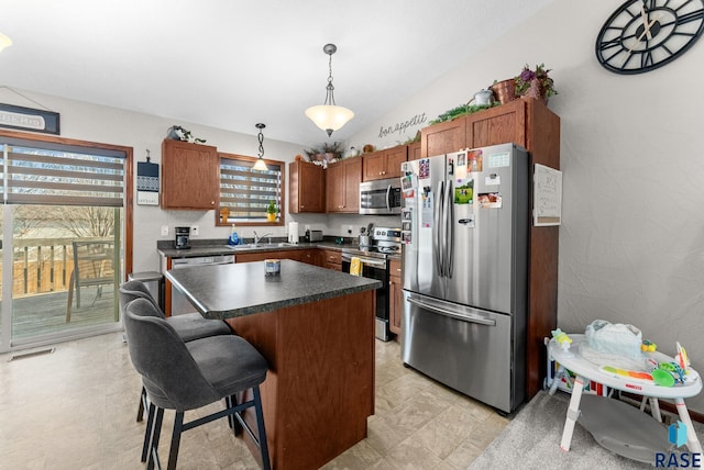 kitchen with sink, decorative light fixtures, a kitchen bar, a kitchen island, and appliances with stainless steel finishes