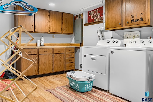 washroom with cabinets, electric panel, light hardwood / wood-style flooring, and washer and dryer