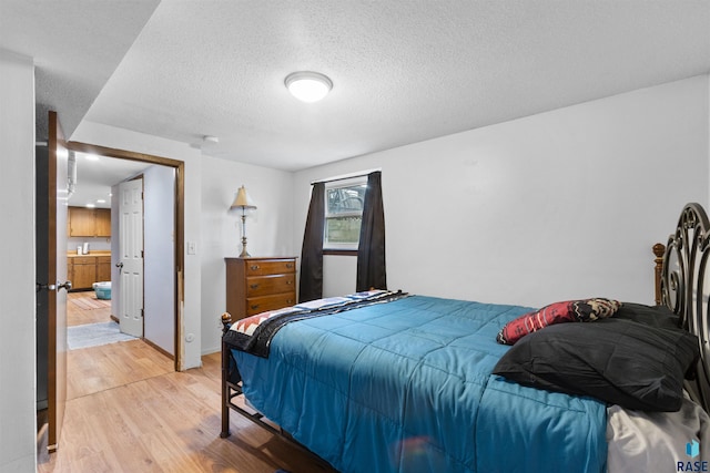 bedroom featuring a textured ceiling and light hardwood / wood-style flooring