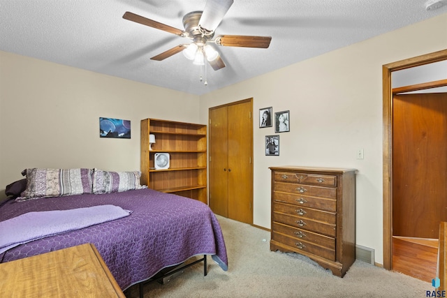 bedroom with ceiling fan, carpet floors, and a textured ceiling