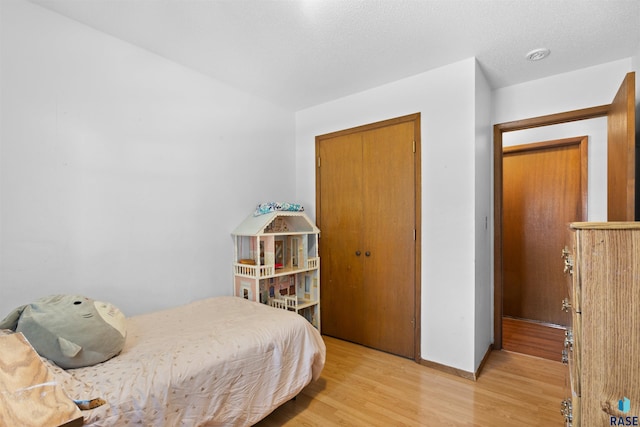 bedroom with light hardwood / wood-style floors and a closet