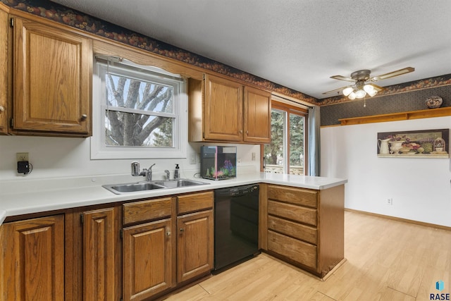 kitchen featuring a textured ceiling, black dishwasher, light hardwood / wood-style floors, sink, and kitchen peninsula