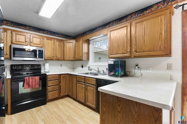 kitchen featuring light hardwood / wood-style floors, kitchen peninsula, a textured ceiling, black appliances, and sink