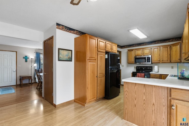 kitchen with ceiling fan, light hardwood / wood-style floors, kitchen peninsula, and black appliances