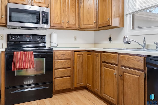 kitchen with sink, light hardwood / wood-style flooring, and black appliances