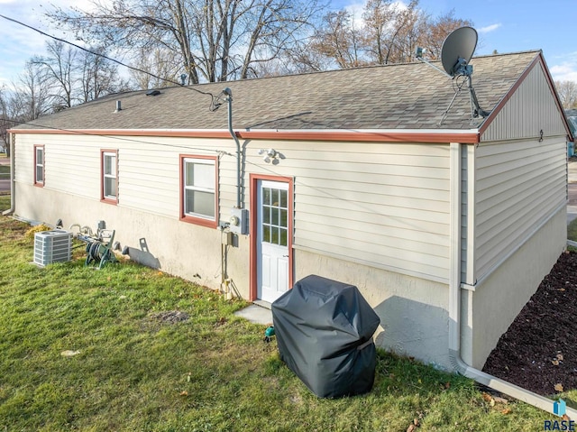 back of house featuring central AC unit and a lawn