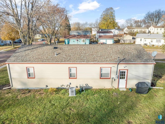 rear view of property featuring central AC unit and a lawn