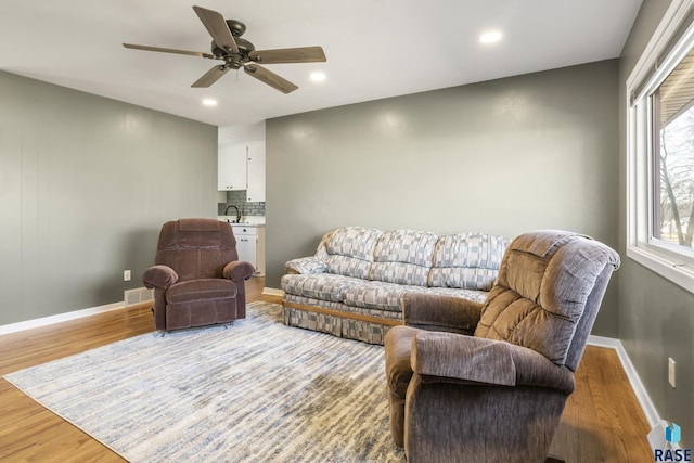 living room with light hardwood / wood-style floors, ceiling fan, and sink