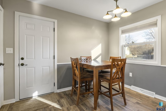 dining space featuring wood-type flooring and an inviting chandelier