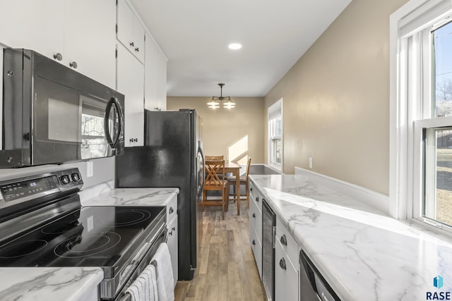 kitchen with decorative light fixtures, stainless steel range with electric cooktop, a notable chandelier, light wood-type flooring, and white cabinets