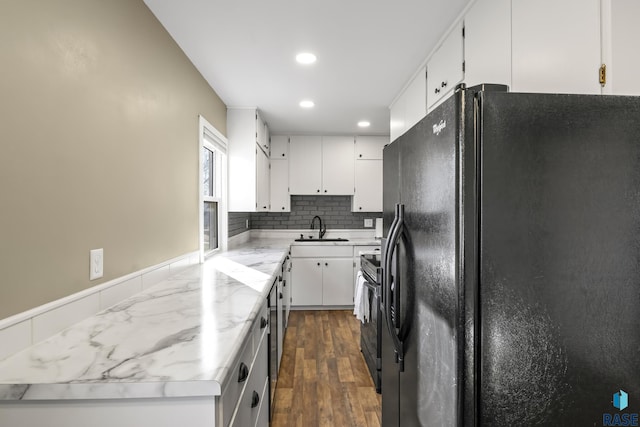 kitchen featuring white cabinets, black fridge, backsplash, and sink