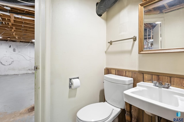 bathroom featuring sink, toilet, and concrete flooring