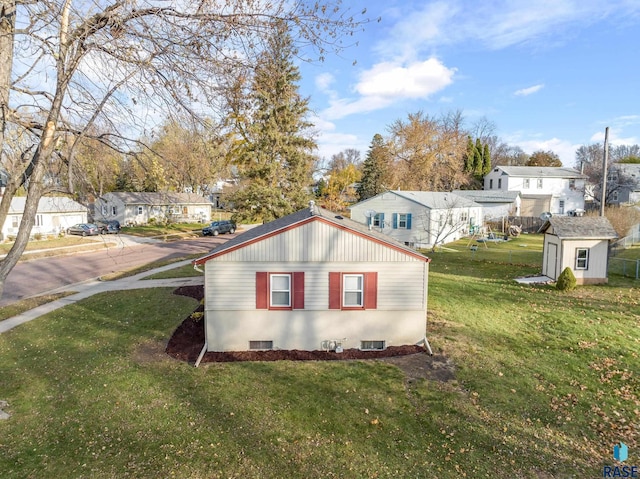 view of side of home with a storage unit and a yard