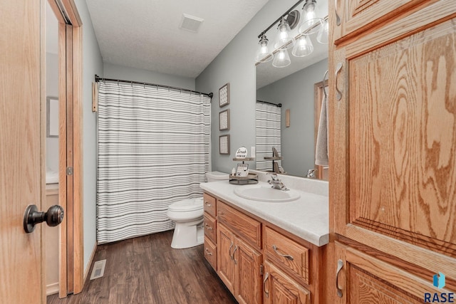 bathroom featuring toilet, vanity, a textured ceiling, and hardwood / wood-style flooring