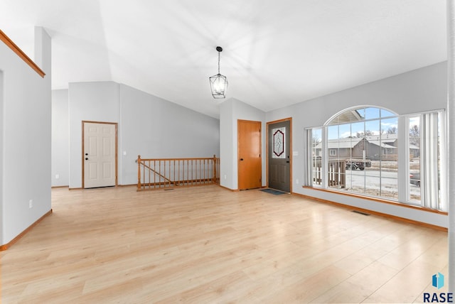 interior space with light hardwood / wood-style floors, vaulted ceiling, and a notable chandelier