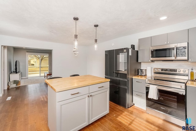 kitchen featuring light hardwood / wood-style flooring, hanging light fixtures, decorative backsplash, gray cabinetry, and appliances with stainless steel finishes