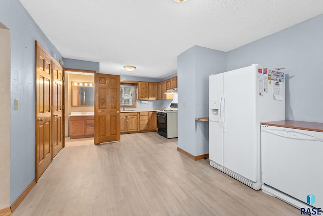 kitchen featuring white appliances, light wood-type flooring, a textured ceiling, and sink