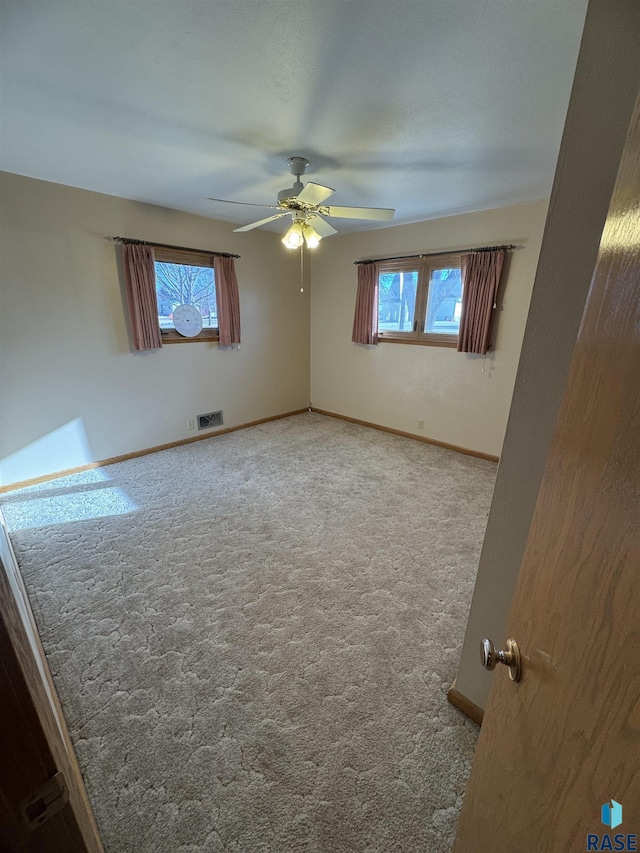 carpeted empty room featuring ceiling fan and a healthy amount of sunlight