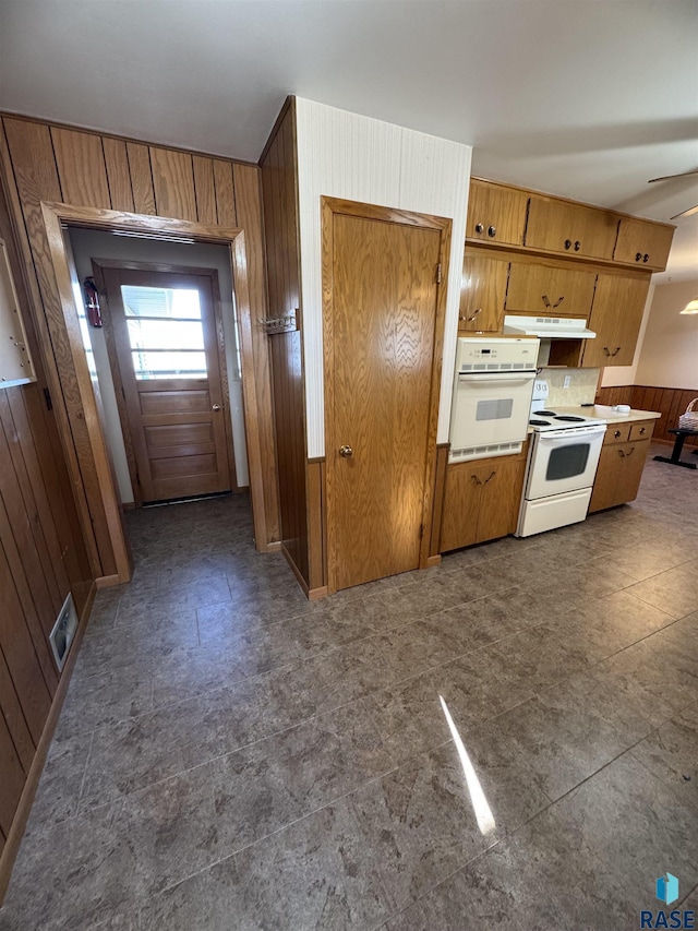 kitchen with white appliances, ceiling fan, and wooden walls