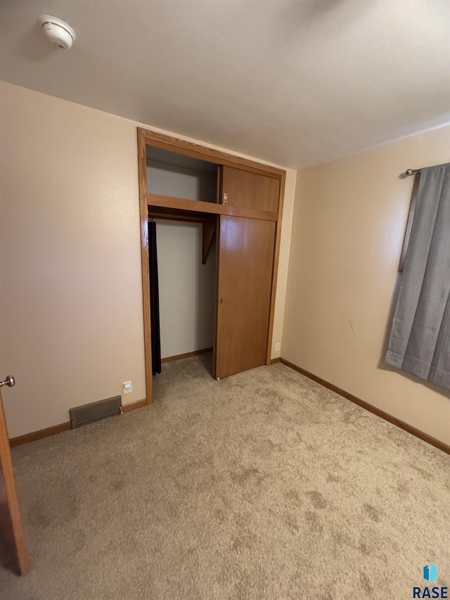 unfurnished bedroom featuring a closet and light carpet