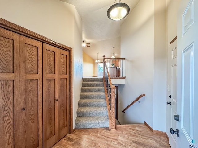 stairway with wood-type flooring, ceiling fan, and vaulted ceiling