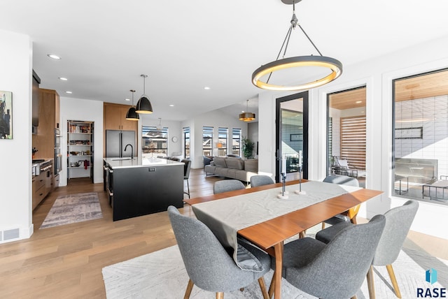 dining space with sink and light wood-type flooring