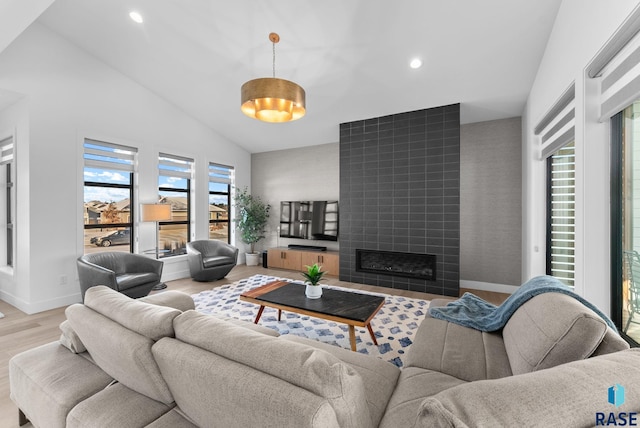 living room with a tile fireplace, high vaulted ceiling, and light hardwood / wood-style floors