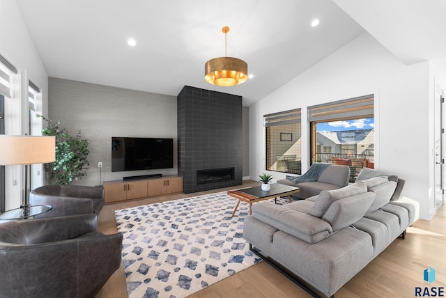 living room featuring lofted ceiling, a tile fireplace, and light hardwood / wood-style flooring