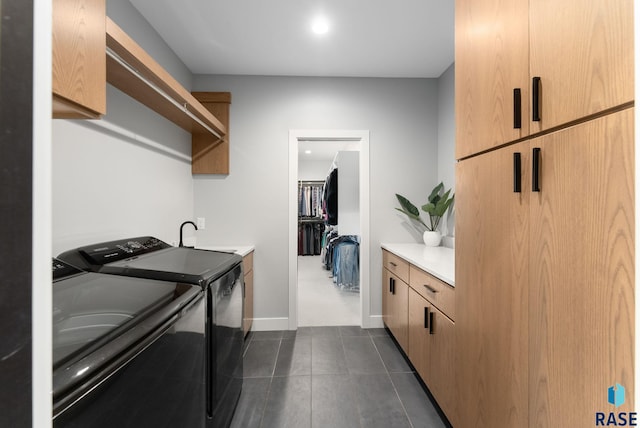 laundry room featuring washer and dryer, dark tile patterned floors, sink, and cabinets