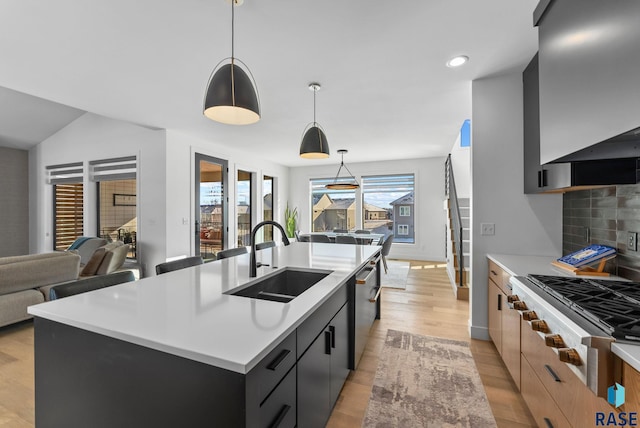 kitchen featuring sink, decorative light fixtures, tasteful backsplash, and a kitchen island with sink