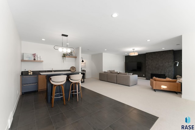 dining room with dark colored carpet, a large fireplace, and bar