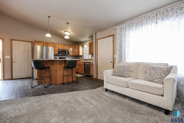 kitchen with hanging light fixtures, a center island, stainless steel appliances, dark colored carpet, and a kitchen breakfast bar