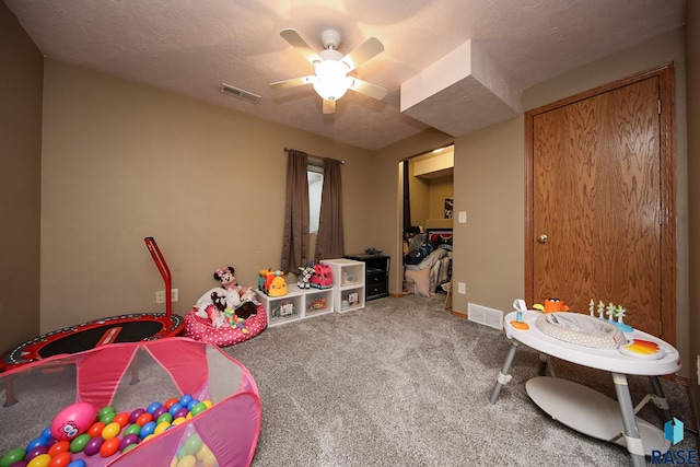 game room with ceiling fan, carpet floors, and a textured ceiling