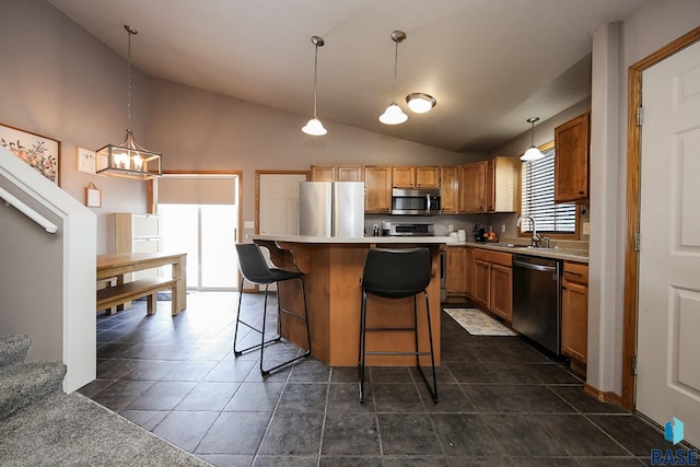 kitchen featuring stainless steel appliances, sink, decorative light fixtures, a center island, and a breakfast bar