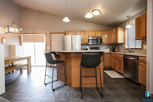 kitchen with stainless steel appliances, sink, decorative light fixtures, a kitchen bar, and a kitchen island