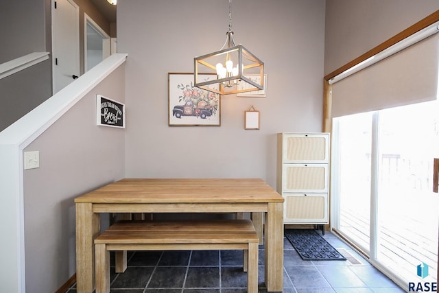 unfurnished dining area with a notable chandelier and dark tile patterned flooring