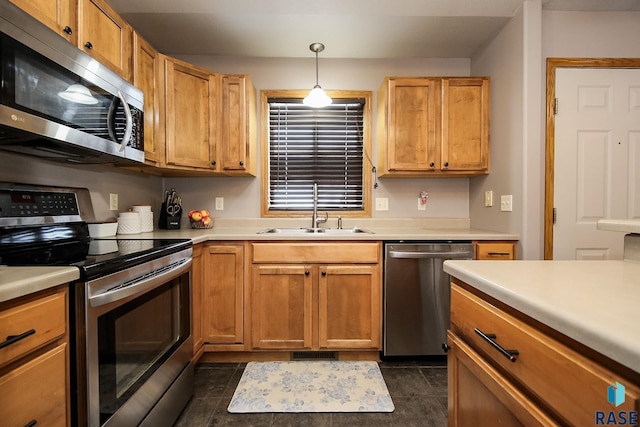 kitchen with appliances with stainless steel finishes, dark tile patterned floors, hanging light fixtures, and sink