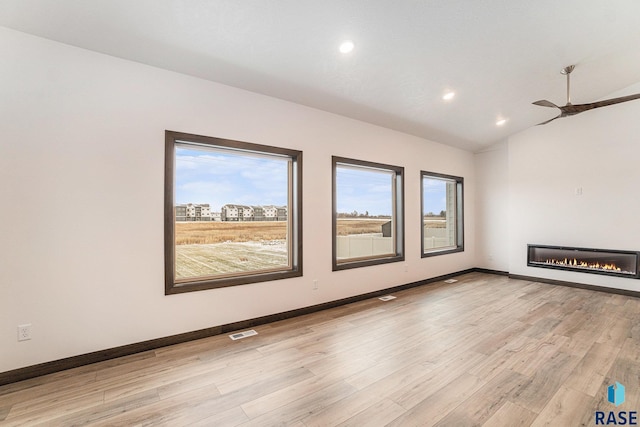 empty room featuring ceiling fan, light hardwood / wood-style floors, and vaulted ceiling