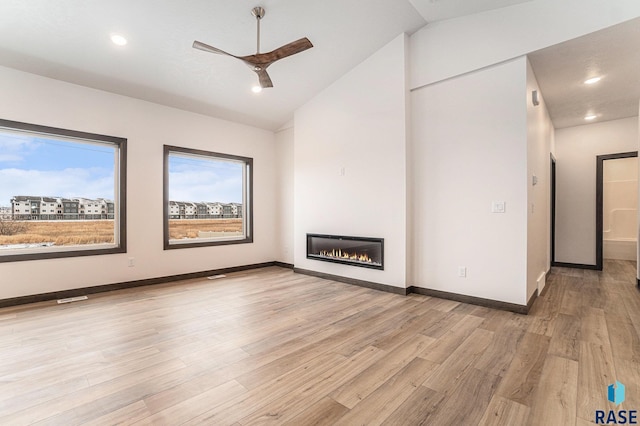 unfurnished living room featuring ceiling fan, light wood-type flooring, and vaulted ceiling