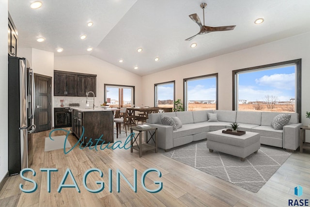 living room with sink, ceiling fan, vaulted ceiling, and light hardwood / wood-style flooring