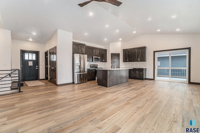 kitchen with light hardwood / wood-style flooring, an island with sink, high vaulted ceiling, appliances with stainless steel finishes, and ceiling fan