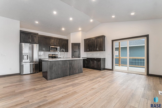 kitchen with light hardwood / wood-style flooring, stainless steel appliances, decorative backsplash, a kitchen island with sink, and dark brown cabinets