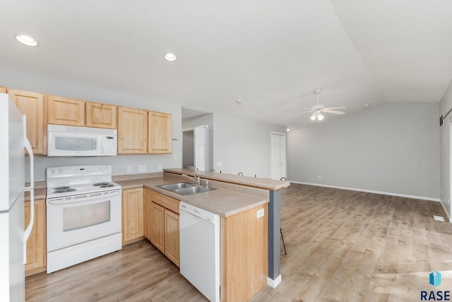 kitchen with white appliances, sink, lofted ceiling, and kitchen peninsula