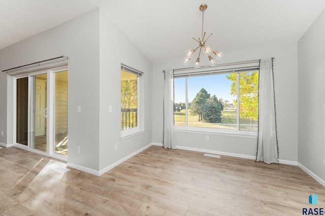 unfurnished dining area featuring a wealth of natural light, light wood-type flooring, an inviting chandelier, and lofted ceiling