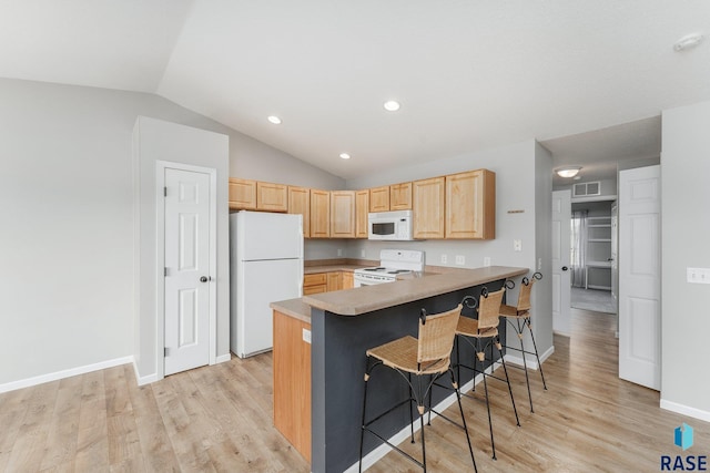 kitchen featuring lofted ceiling, light brown cabinets, white appliances, a kitchen bar, and kitchen peninsula