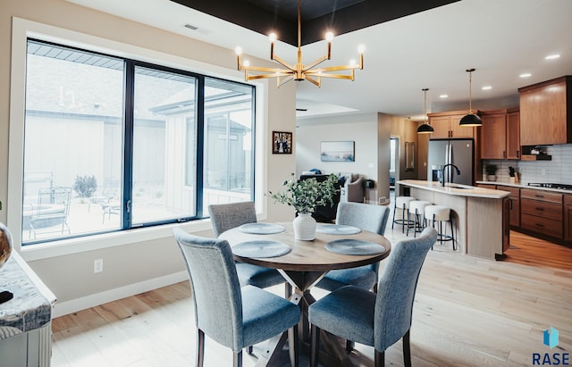 dining space featuring light hardwood / wood-style floors, sink, and a chandelier