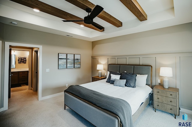 carpeted bedroom featuring ensuite bath, ceiling fan, and beamed ceiling