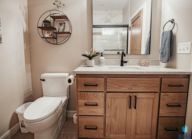 bathroom featuring a shower with shower door, vanity, and toilet